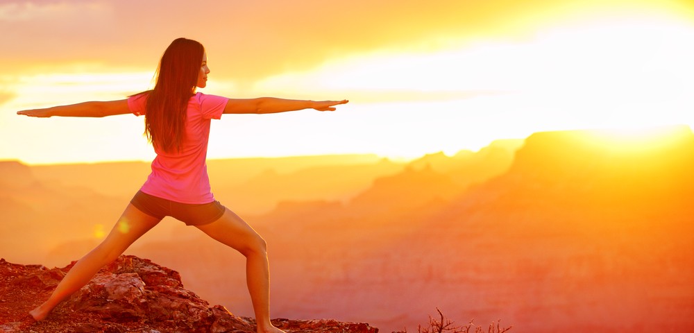 Yoga woman meditating at sunset in Grand Canyon. Female model meditating in serene harmony in warrior pose. Healthy wellness lifestyle image with multicultural young woman. From Grand Canyon, USA