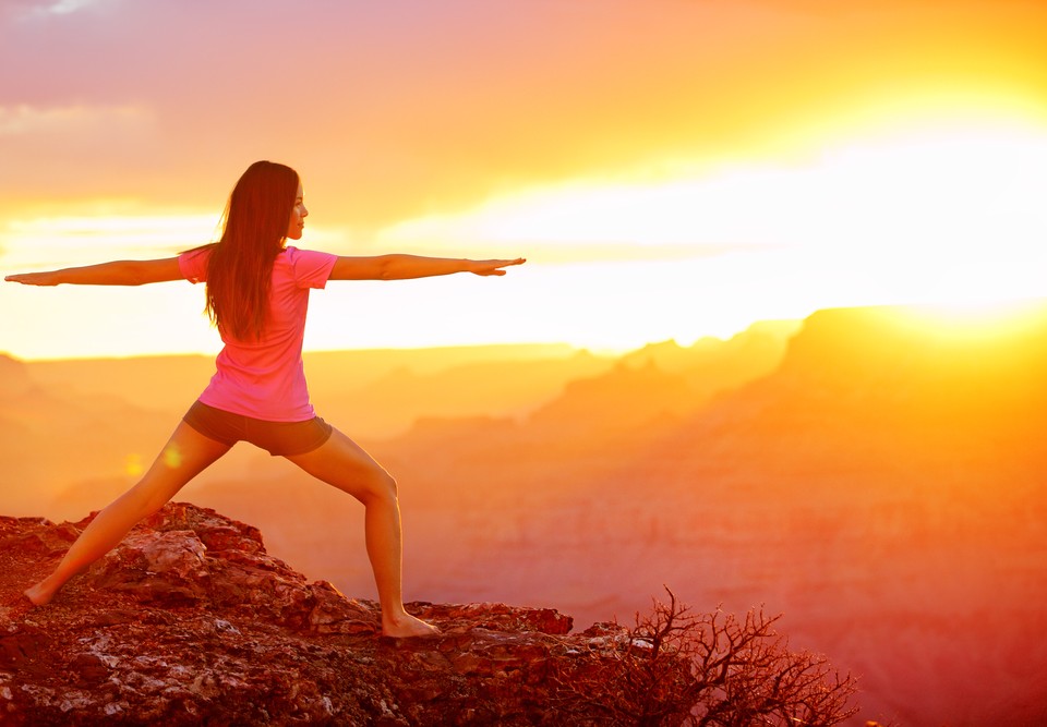 Yoga woman meditating at sunset in Grand Canyon. Female model meditating in serene harmony in warrior pose. Healthy wellness lifestyle image with multicultural young woman. From Grand Canyon, USA