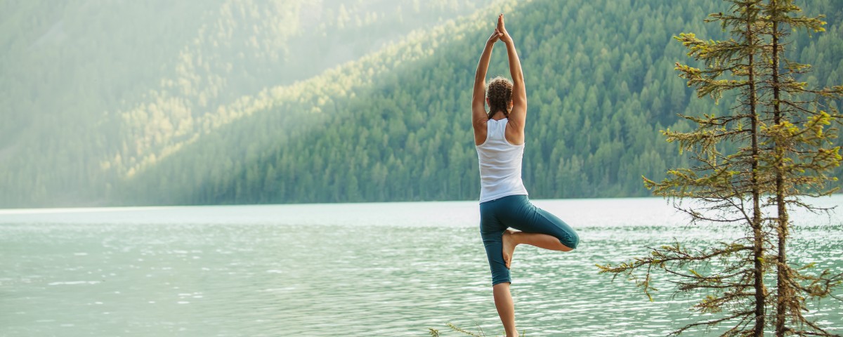 Young woman is practicing yoga at mountain lake