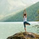 Young woman is practicing yoga at mountain lake