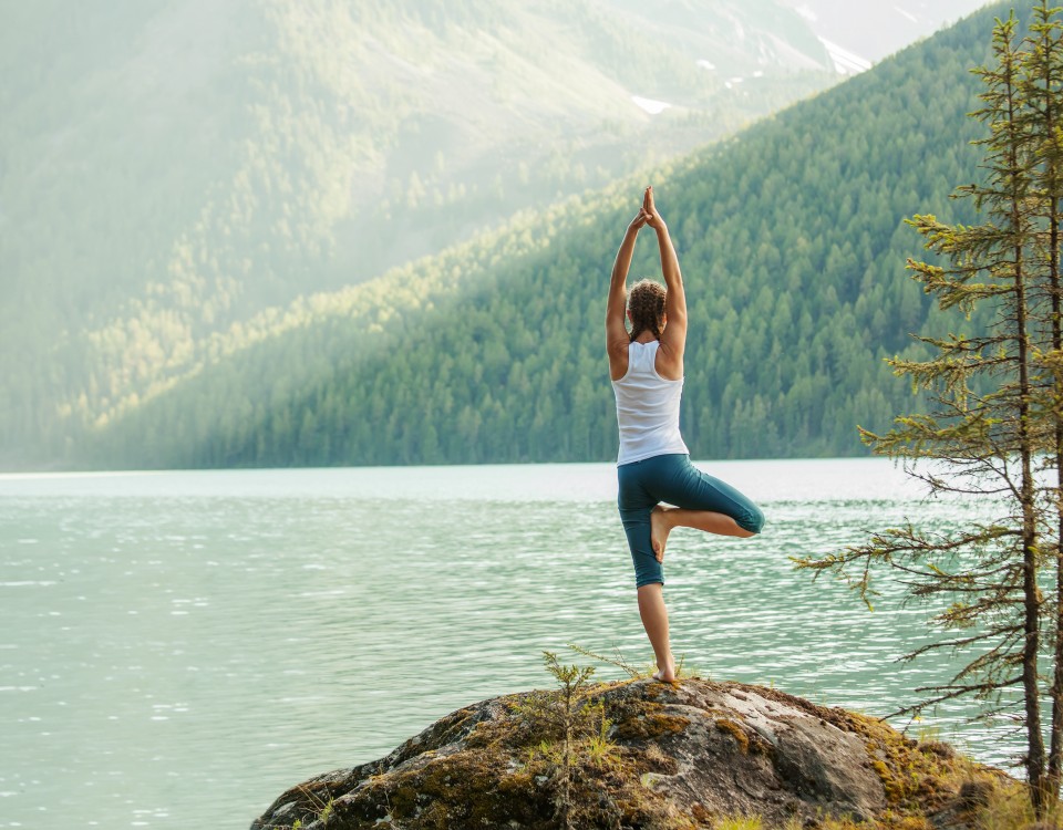 Young woman is practicing yoga at mountain lake